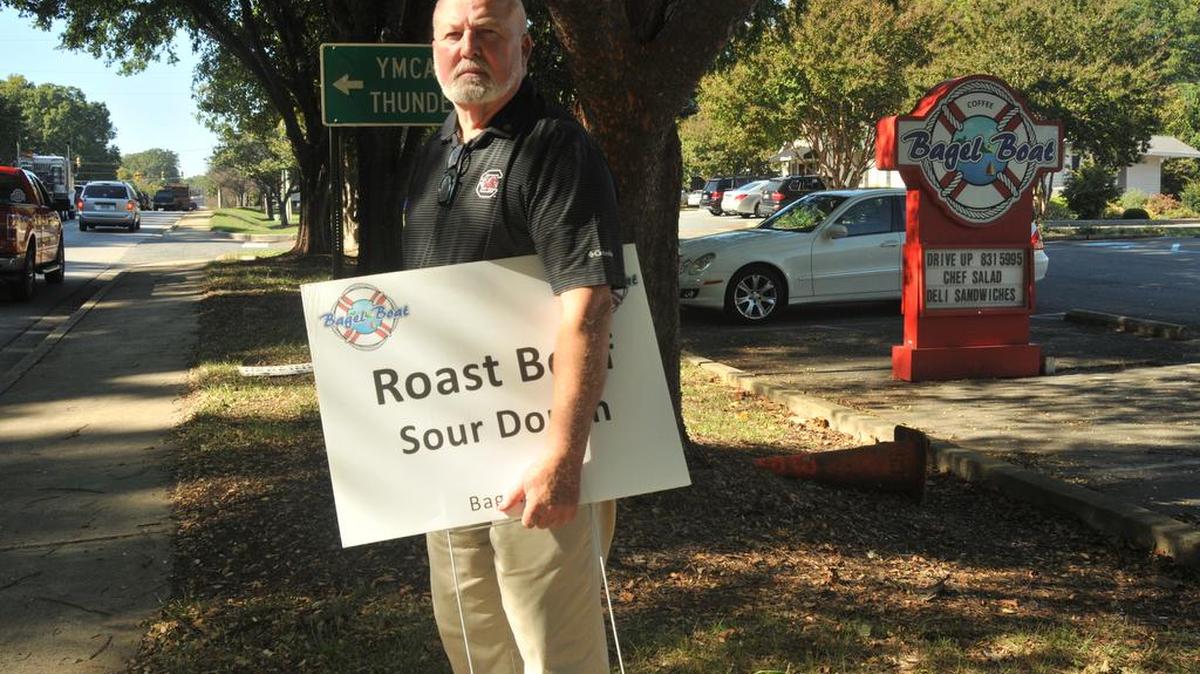 Frank Keefe, owner of Bagel Boat on Charlotte Highway, stands with a sandwich sign near the road where he is prohibited by York County codes to place signage.