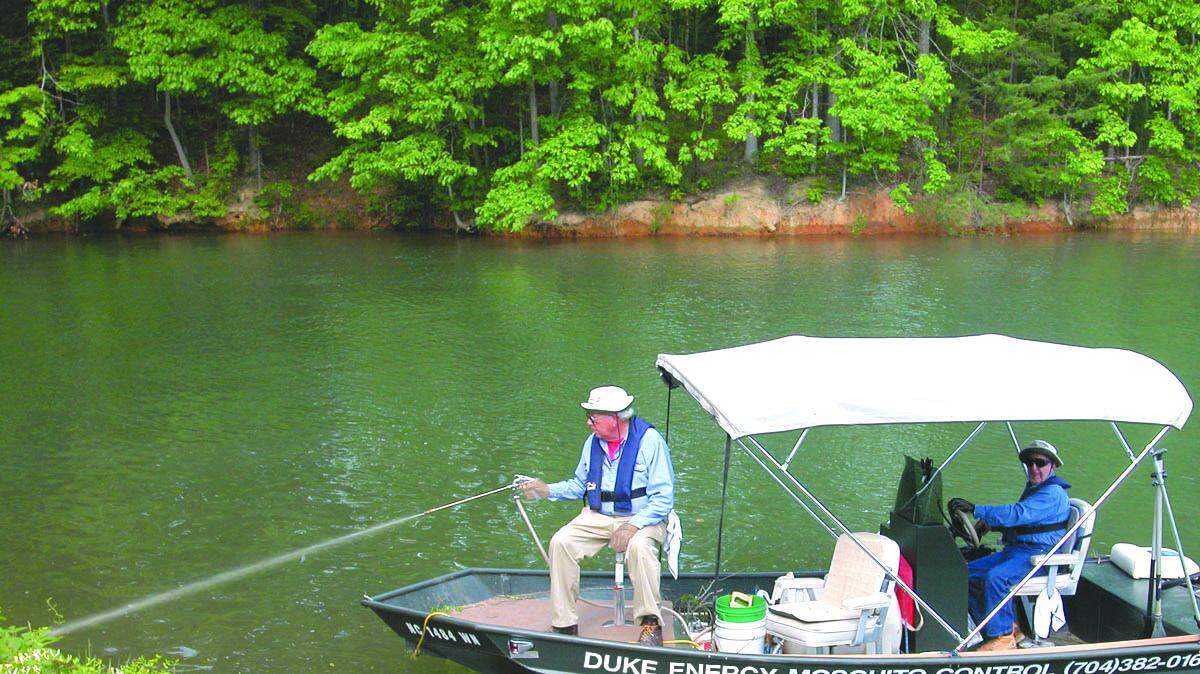 Members of Duke Energy mosquito control team spray breeding habitat along the shoreline of Lake Wylie.
