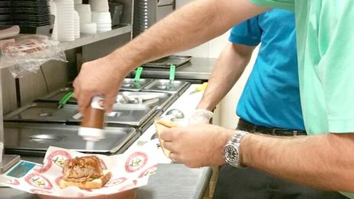 
Robb Stamey puts the finishing touches on a “Big Dad,” a half-pound barbecue sandwich named after founder Shane Thompson’s father, Dewey “Big Dad” Brown. Stamey owns three area Shane’s Rib Shack restaurants.
