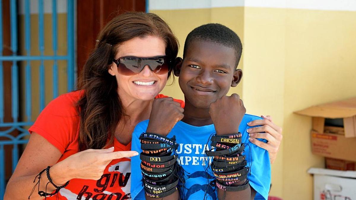 
Michelle Cherikos spends some time with Ismael, who shows off the bracelets he creates and sells for $5 to support himself and his brother in Haiti. Fort Mill township residents have purchased the bracelets from Cherikos.
