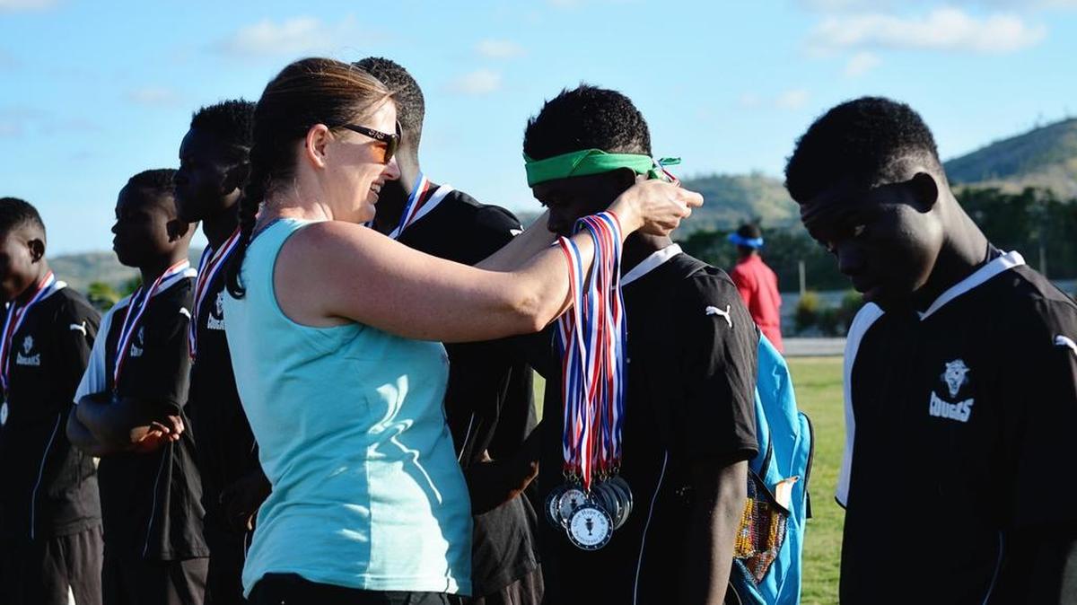 Fort Mill’s Angela Quinn awards medals to members of the Cambry Orphanage soccer team, which won a tournament in Haiti wearing uniforms donated by York Comprehensive High School.