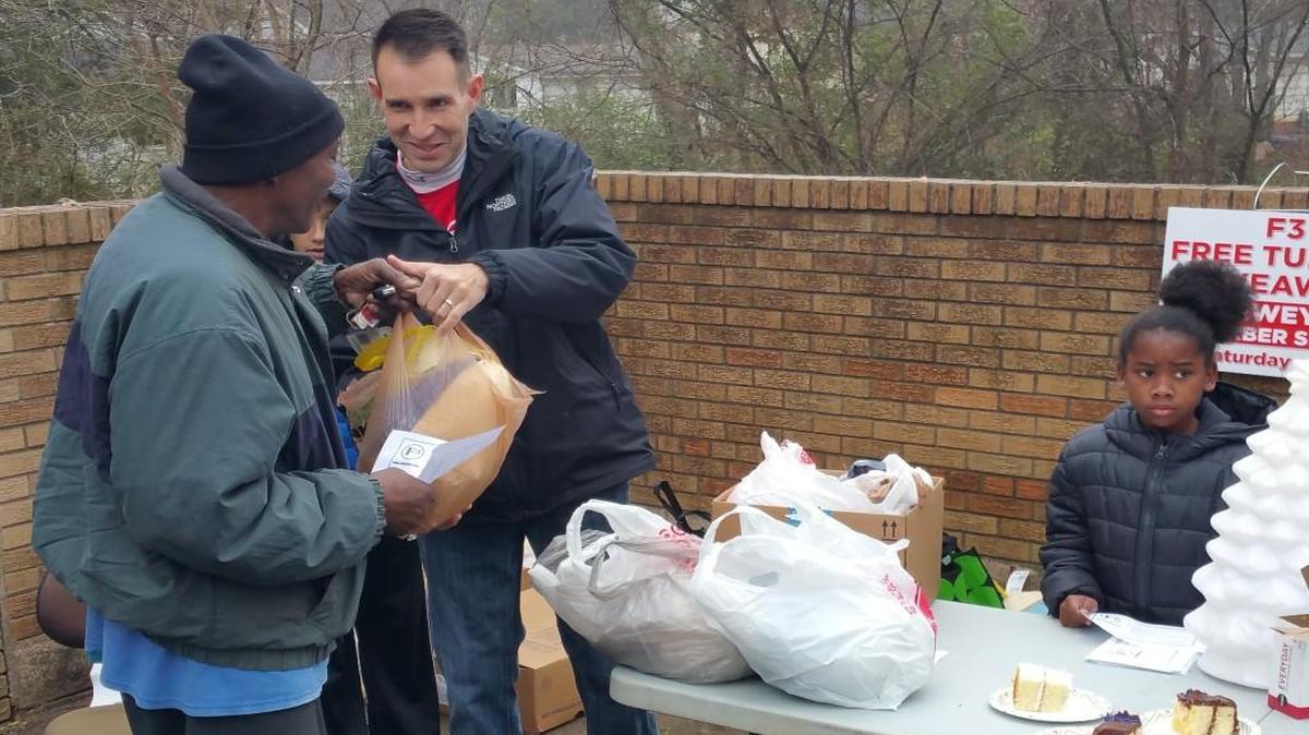 F3 member Phillip Elliot, right, hands a turkey to a Paradise resident the weekend before Christmas, while Sydnee Belton, daughter of F3 member Montrio Belton, helps hand out pieces of cake.