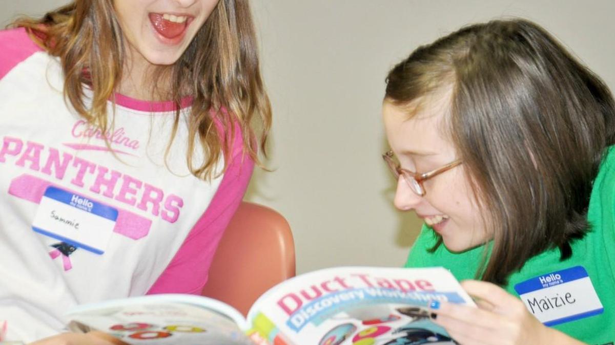 Sammie Noble, left, and Maizie Schoonmaker, both of Lake Wylie, laugh while looking through a duct tape book of craft ideas at Lake Wylie Public Library. The library is offering longer hours effective March 20