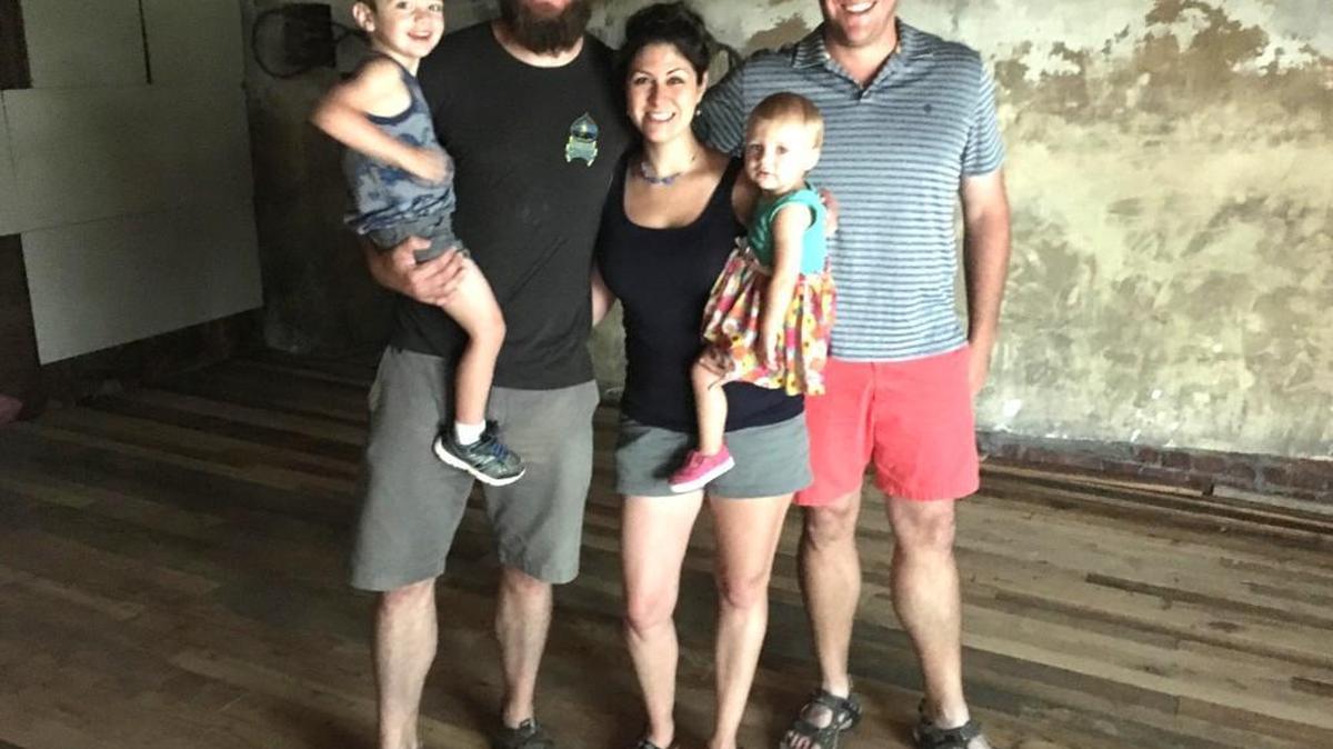 The Tolson family, Travis, holding his son Carter, his wife Khara, holding their daughter Stevie, and his brother Steve, inside the Main Street storefront they are transforming into the first brewery inside Fort Mill town limits.