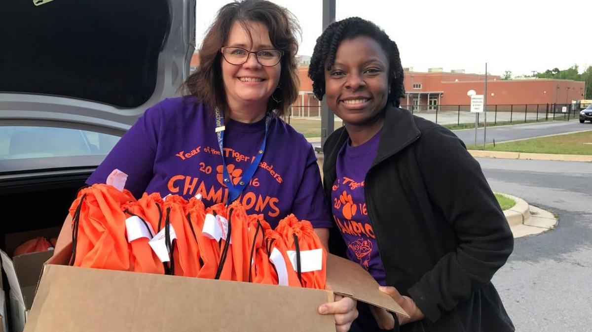 Shelly Thompson and Jessica Wiggins McCreary load up bags of books for their Reading Recovery students. Books were provided through Clemson football coach Dabo Swinney’s Tigers Read Project.