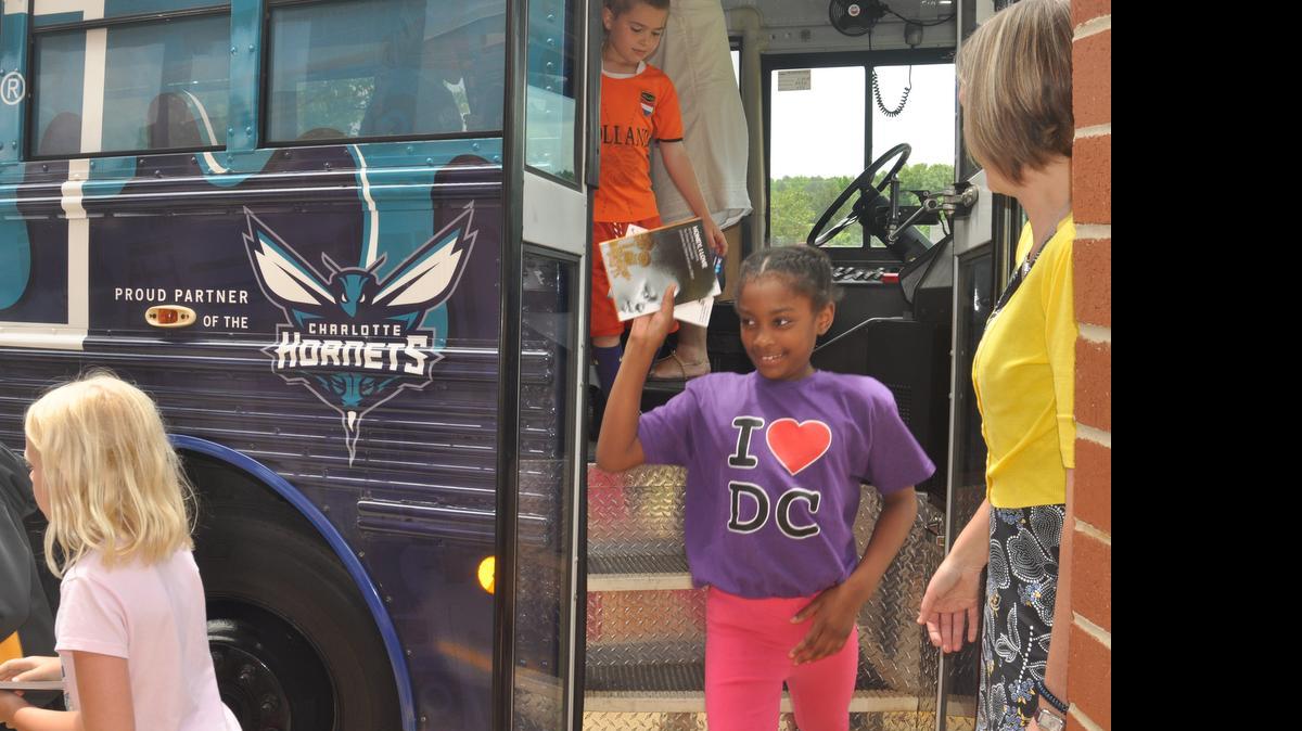 
Justice “Symone” Collier, a second grader at Crowders Creek Elementary School, walks off the Hornets and Lowe’s Book Bus after an assembly May 19. She had read 470 minutes since May 4.
