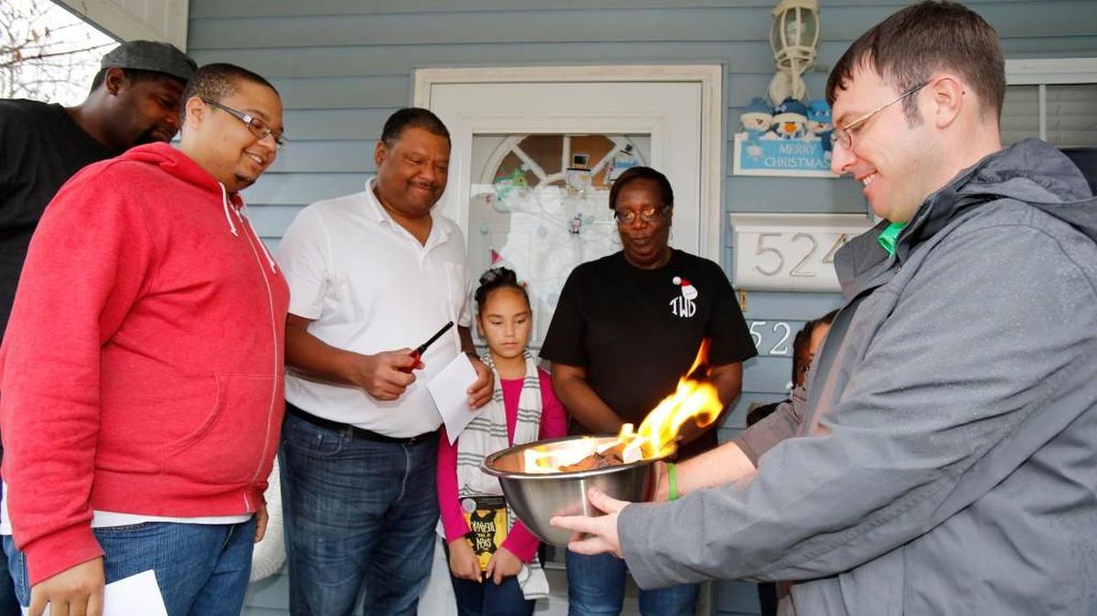 The Walker family of Fort Mill celebrated paying off their house, built by Habitat for Humanity, by burning the mortgage Monday. Tim Veeck, right, executive director of Habitat for Humanity of York County, holds the bowl with the burning mortgage as homeowners Kenneth Walker, holding the lighter, and his wife Tournorris and their family watch.