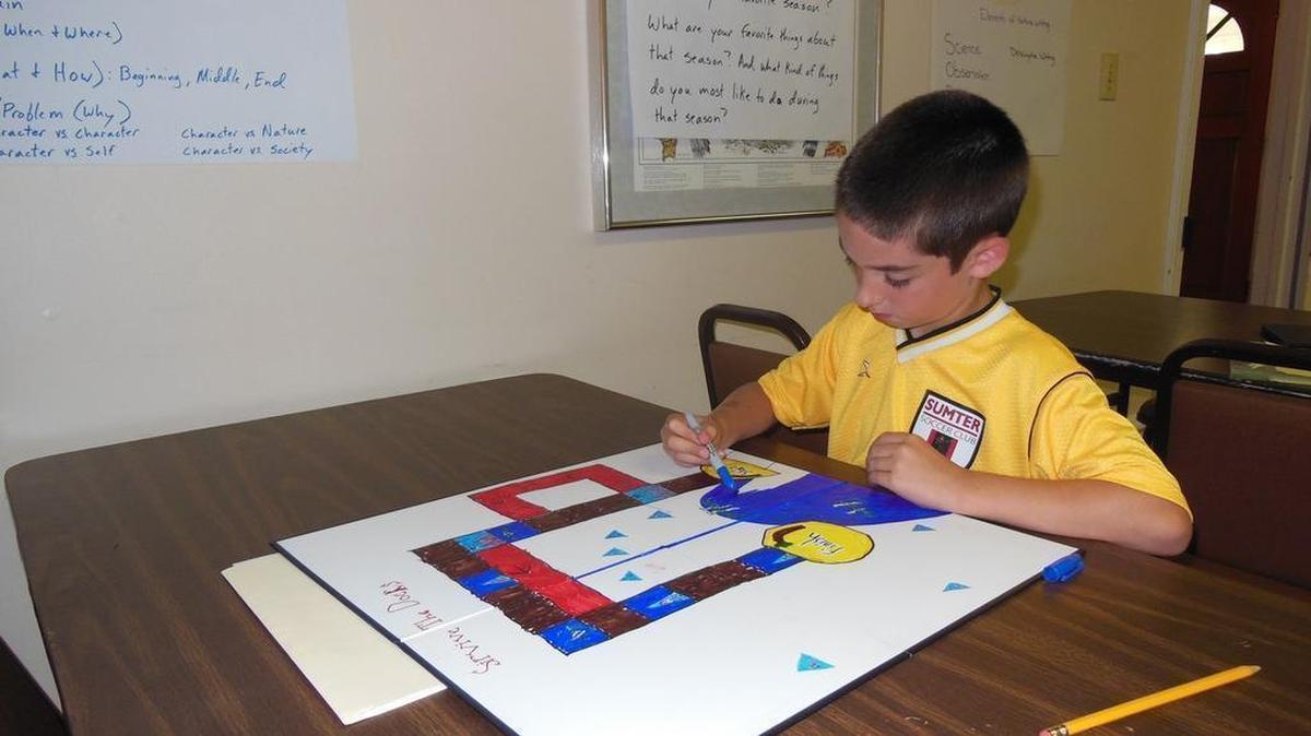
Wyatt Eckhardt, 8, colors in the water on the board game he created called Survive the Docks. Eckhardt used what he learned about sharks and eels in school to come up with the concept for the game he made during a Young Writers’ Academy summer camp at the Anne Springs Close Greenway.
