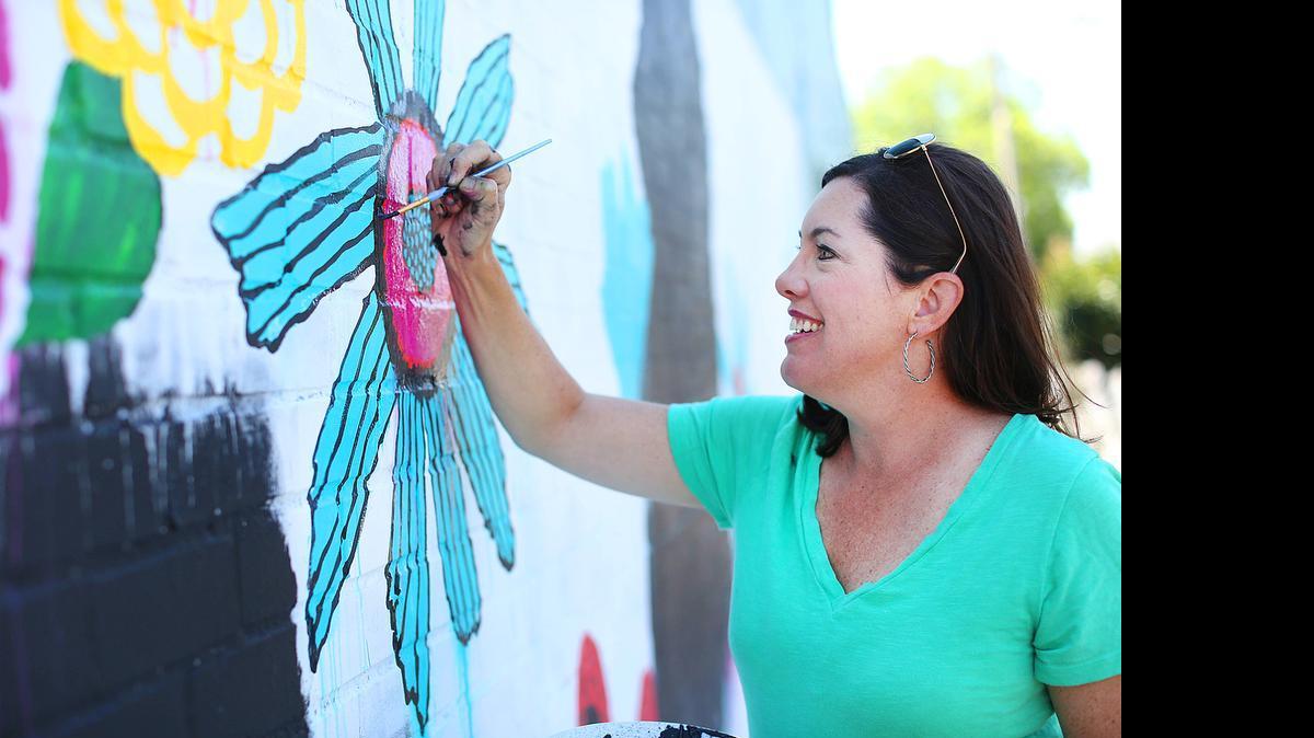 
Artist Caroline Simas works on her mural on the Crossings on Main building.
