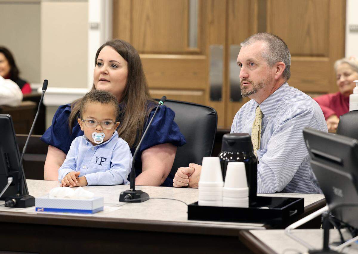 Kendal Farmer, left, holds 2-year-old Billy Farmer while John Farmer listens to the judge Wednesday at York County Family Court, where the couple legally adopted the toddler.