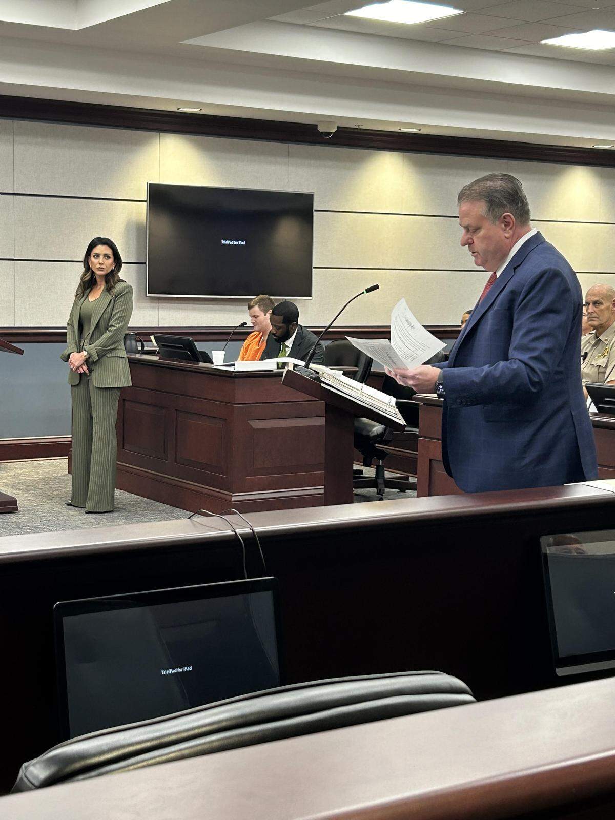 Zachary East Elias, seated in orange, in York County, South Carolina criminal court on Sept. 15, 2025. 16th Circuit Solicitor at right explains the murder and other charges against Elias as his lawyers stand and sit with Elias. Elias, 29, of Columbia, is accused of killing two people and wounding another at a Rock Hill smoke shop in December 2024.