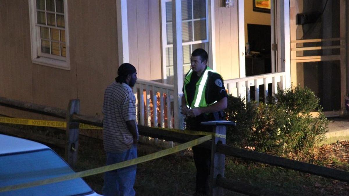 A Lancaster police officer speaks with an unidentified man outside a Miller Street home where 2 people were shot early Sunday morning. No arrests have been made.