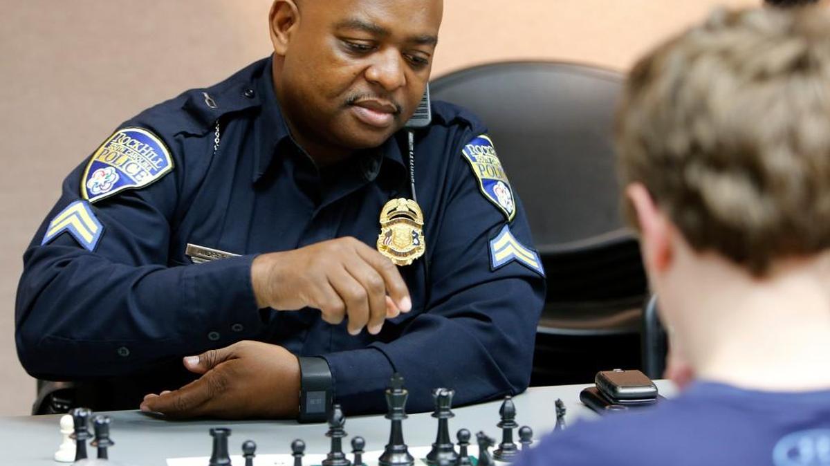 Rock Hill Police Officer William Andrews plays chess Tuesday with Matt Thigpen, 12, at the York County Library as part of the RHPD Got Game! program.