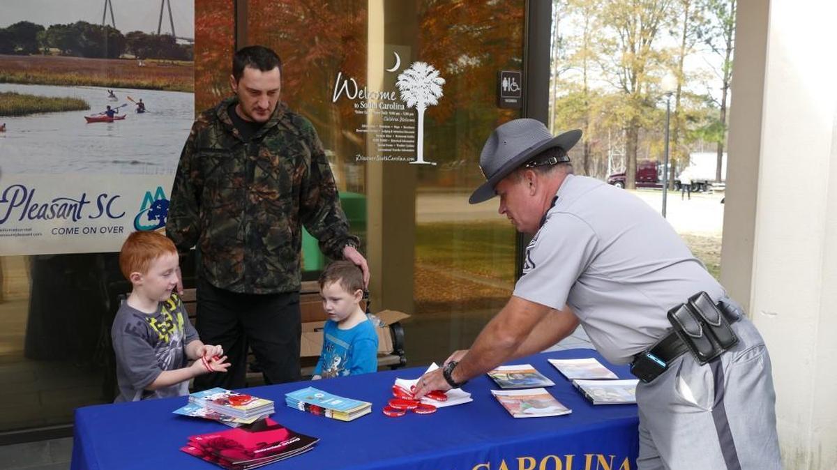 Lance Cpl. Gary Miller of the S.C. Highway Patrol, right, gives rubber bracelets and travel safety information to Dennis Laforest and his sons Nicholas, left, and Tyler at the welcome center on Interstate 77 in the Fort Mill area. Troopers are setting up safety breaks around the state Wednesday as holiday travelers get on the road.