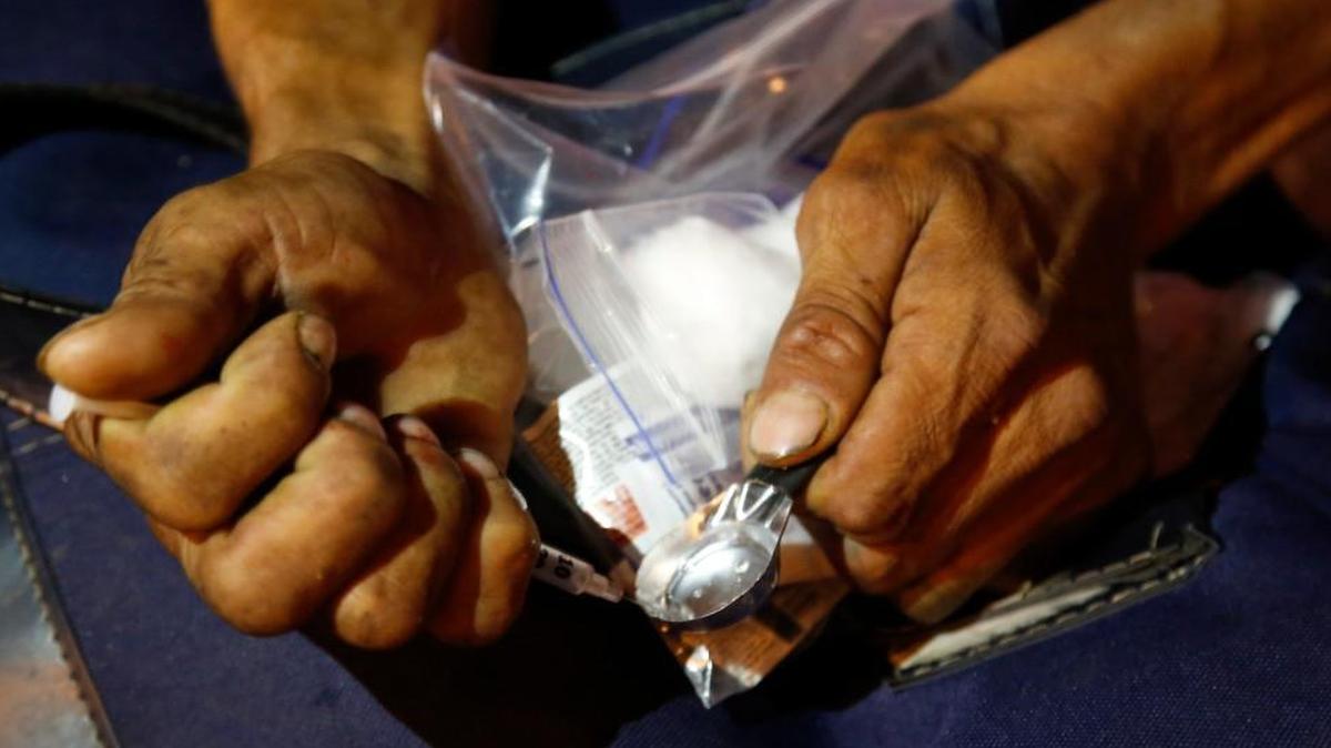 A drug addict prepares shoot up heroin after receiving a kit including a spoon, a rubber tube, cotton, sterilized water and clean syringes distributed by a program sponsored by the Open Society Foundation and government agencies in Dosquebradas, Colombia.