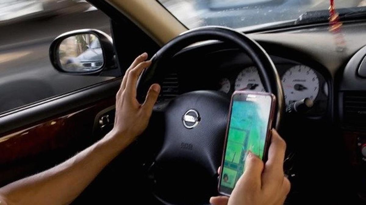 A man holds his smartphone as he uses the “Pokémon Go” mobile phone application while driving.
