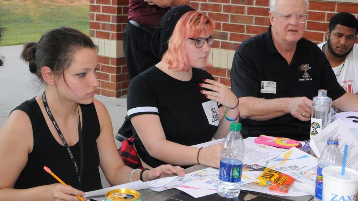 Student Ideas Group members Gi Gi Strollo, left, Candance Otten and Charles Johnson talk about their e-commerce project to raise money for Rock Hill schools.