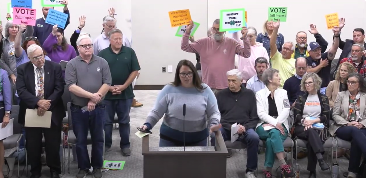 Residents hold up signs Monday night asking York County Council to increase school impact fees in the Clover district.