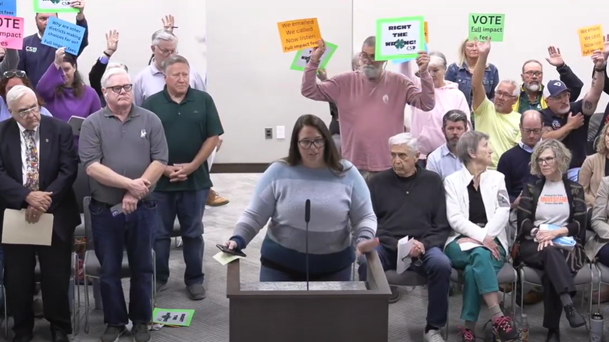 Residents hold up signs Monday night asking York County Council to increase school impact fees in the Clover district.