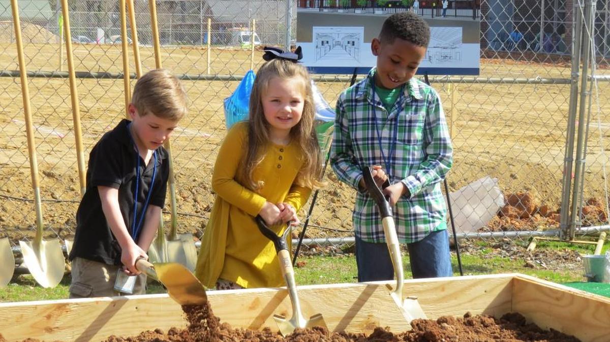 The Children’s School students Hampton Smith, Mattie Zo Herring, and Brandon Solomon shovel dirt at the site of their soon-to-come Montessori building.