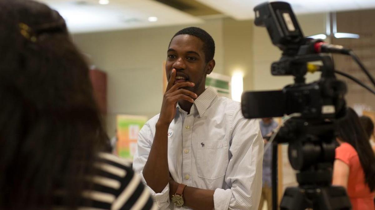 2016 McNair Scholar Camerun Washington, a 2017 Winthrop graduate, being interviewed by Winthrop Close-Up about his research during an April poster presentation. McNair scholars may present their research throughout the year.