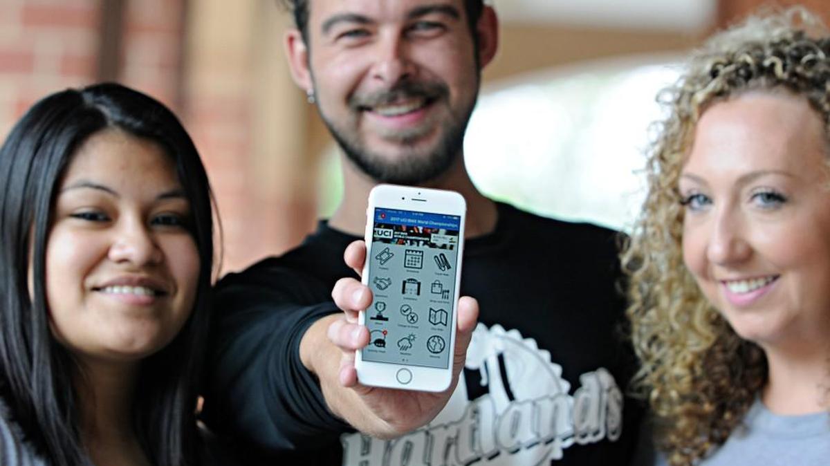 Hartland's Sports Bar employee Chip Moxley, center, holds a phone with the 2017 UCI BMX World Championship App next to Yuli Aguilarand, left, and Kristen Howe Friday at the Rock Hill restaurant. Hartland's is one of the restaurants featured on the app.