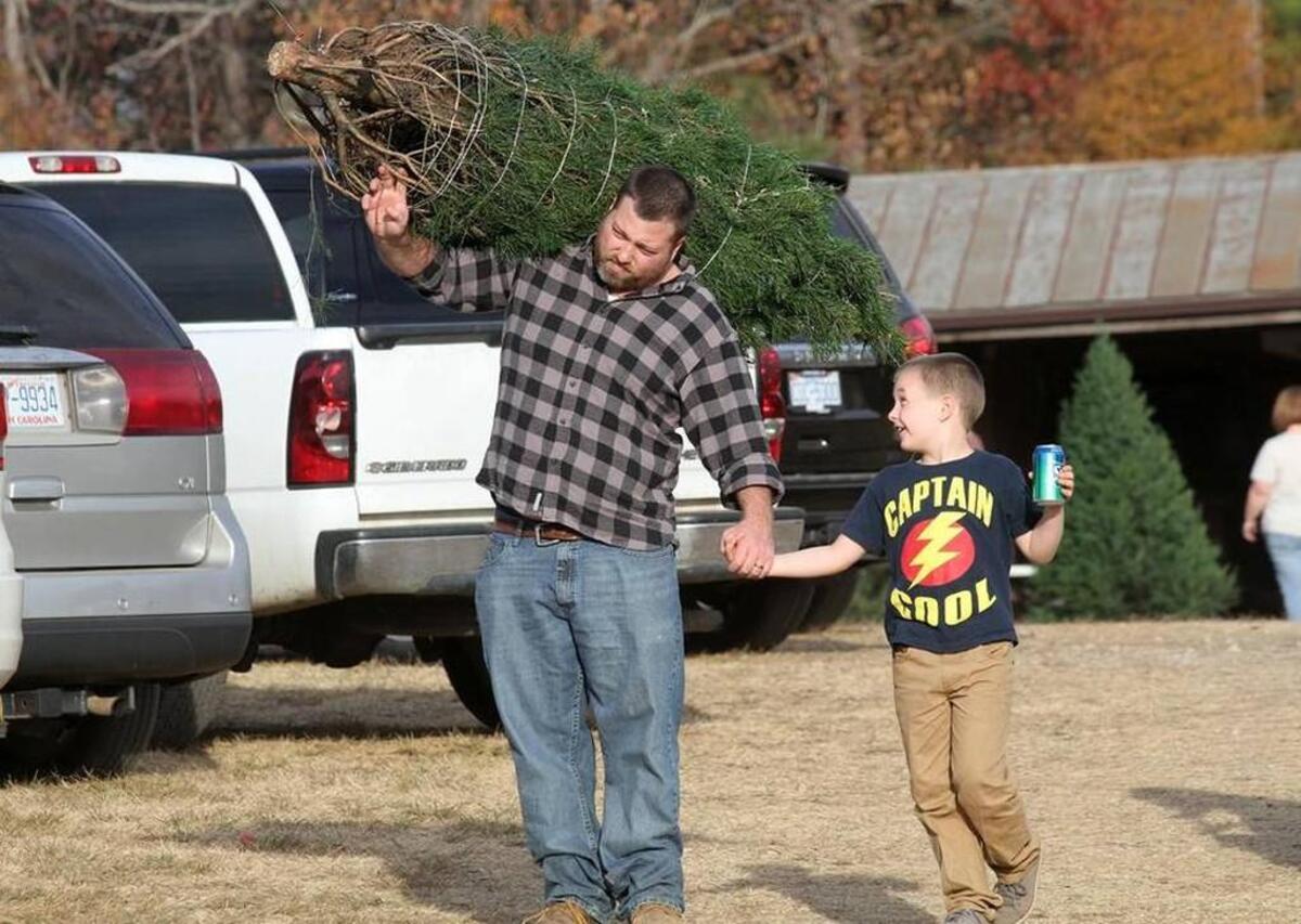 Visitors at Penland Christmas Tree Farm in York County walk to their car with a new tree earlier this month.