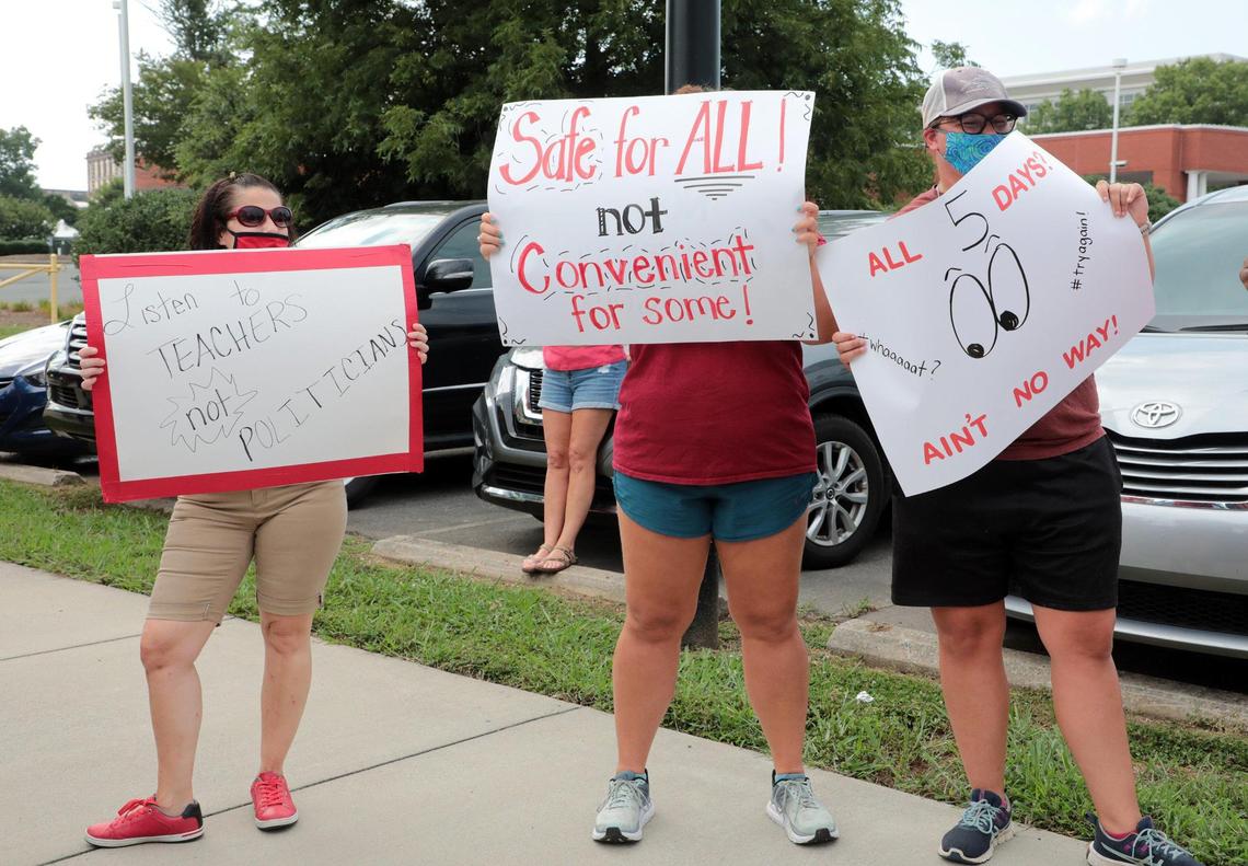 In this file photo, protesters hold signs outside while the Rock Hill school board meets on Thursday, July 16, 2020.