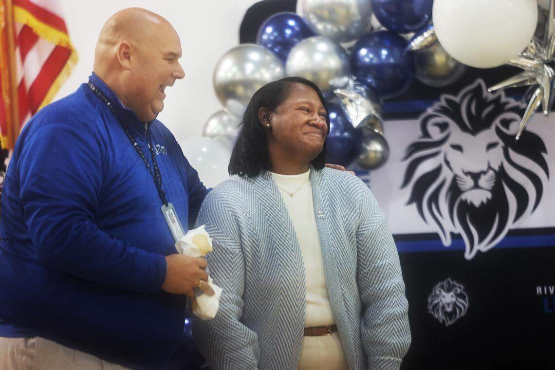 Richard Ball, high school principal at Riverwalk Academy, congratulates Erica McCray Tuesday as the elementary school principal at Riverwalk receives a $25,000 Milken Educator Award.