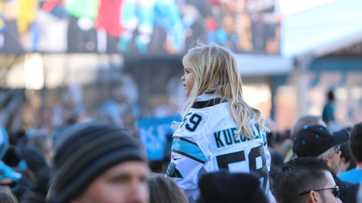 A young fan in a Luke Kuechly jersey waits for the start of the Panthers Pride Rally at Romare Bearden Park on Friday.