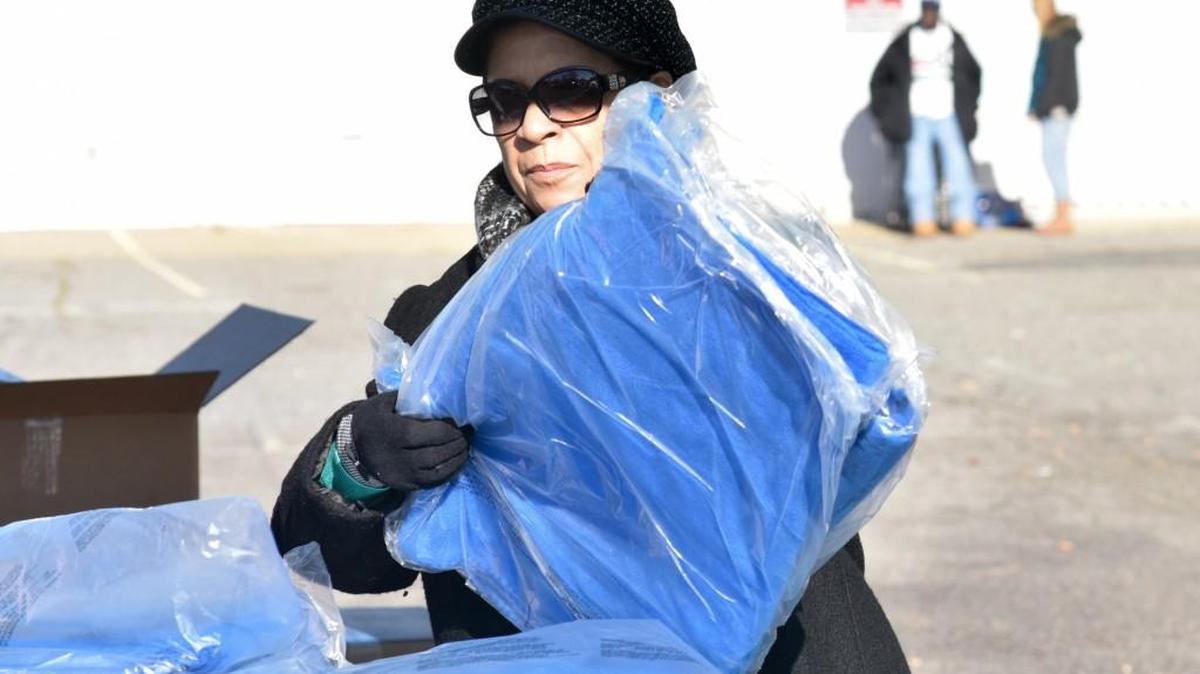 Anna Rosado, a volunteer for Molina Healthcare, sorts a stack of blankets to be distributed to waiting clients of Renew our Community Tuesday afternoon in the ROC parking lot.