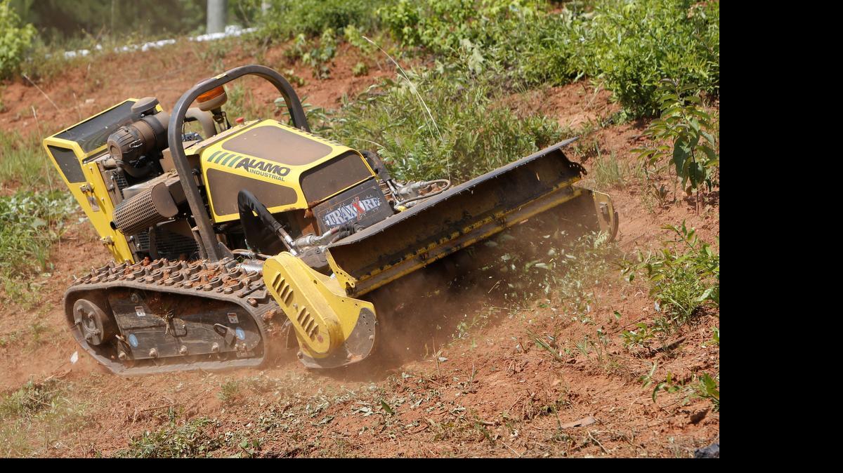 
Seth Grant operates a remote-controlled lawn-mowing robot along I-77 near Dave Lyle Blvd. The mower is owned by contractor Dixie Lawn Service out of Kings Mountain.
