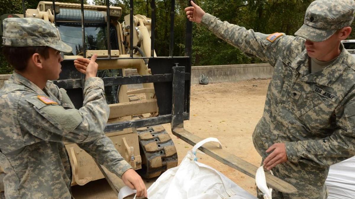U.S. Army Spc. John Adams and Spc. Austin Jones from the South Carolina National Guard’s 1782nd Engineer Company from Lancaster, use hand signals to communicate to Spc. Dermaine Cherry, forklift driver, as they continue repairs on a section of Whitehouse Road, near the Richland Wastewater Treatment Plant in Columbia on Oct. 13.
