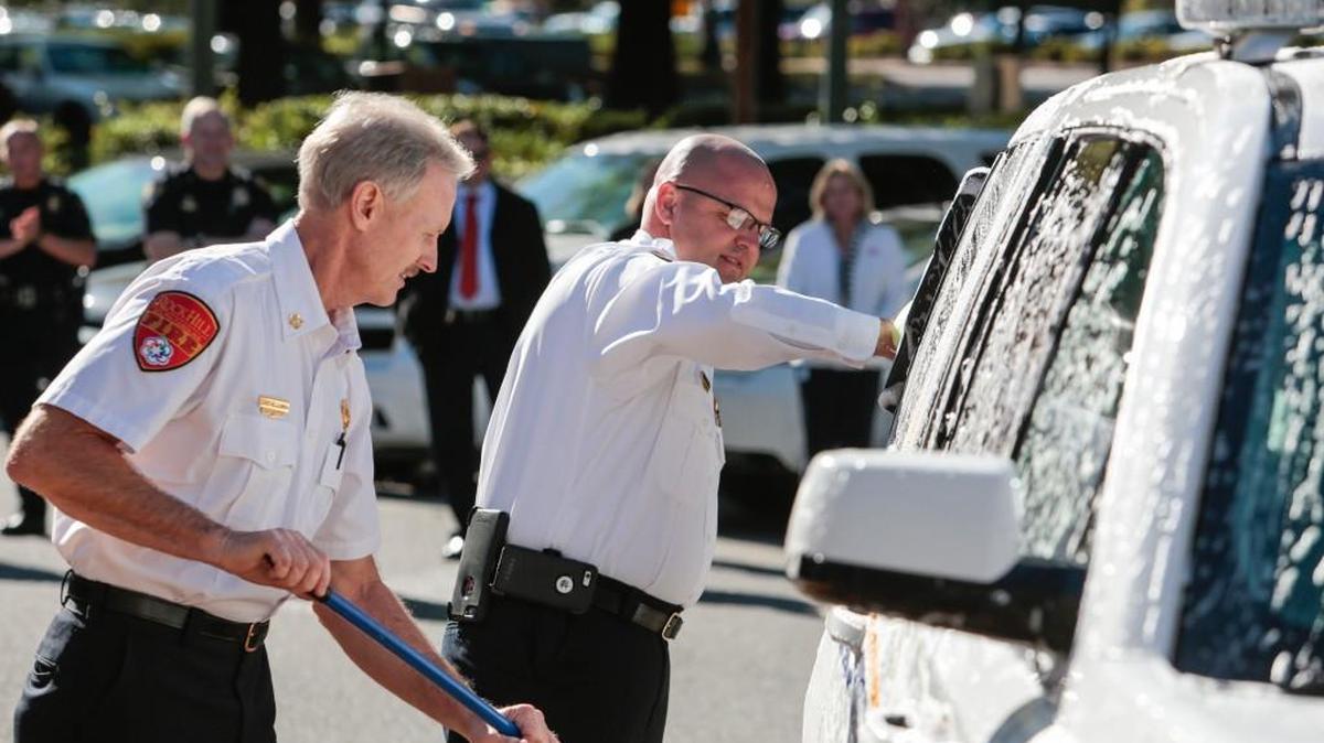 
Rock Hill Fire Department Chief Mike Blackmon, left, and Battalion Chief Chris Channell, right, settle a bet Monday by washing a police car after losing a charity soccer game against the Rock Hill Police Department.
