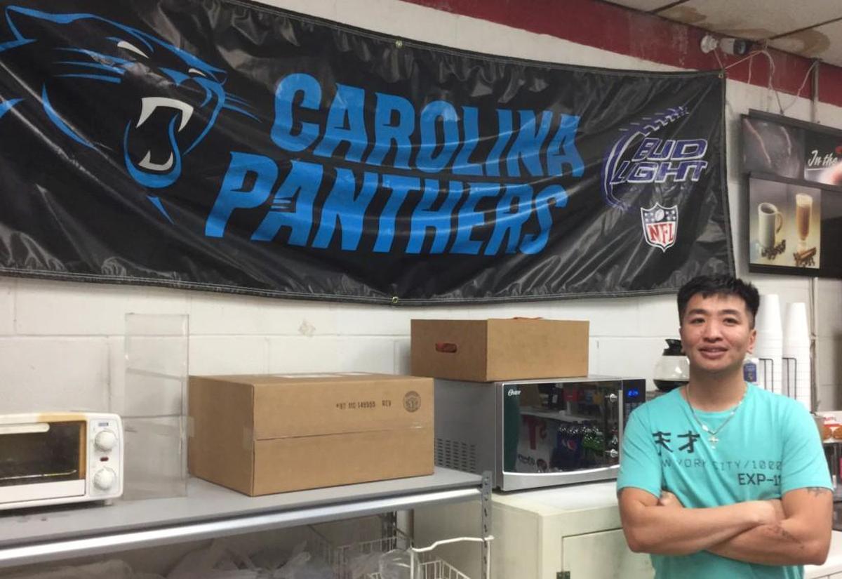 Huy Pham, who owns and operates H & H Mart on Willowbrook Avenue in Rock Hill, proudly shows off his support for the Carolina Panthers.