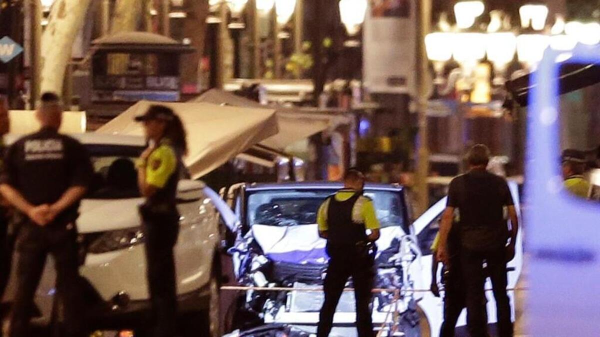 Police officers stand next to the van involved on an attack in Las Ramblas in Barcelona, Spain, Thursday, Aug. 17, 2017. A white van jumped up onto a sidewalk and sped down a pedestrian zone Thursday in Barcelona's historic Las Ramblas district, swerving from side to side as it plowed into tourists and residents. Police said 13 people were killed and more than 50 wounded in what they called a terror attack.