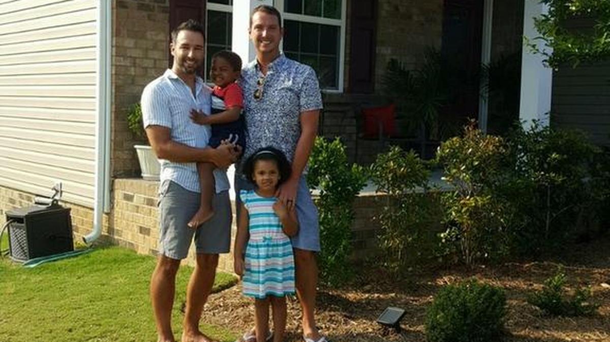 The Lamonica family at home in Rock Hill on Monday evening. A gay pride flag waves above them. Left, Eric Lamonica, holding son Jasper. Right, Jerry Lamonica, with daughter Ellie in front.