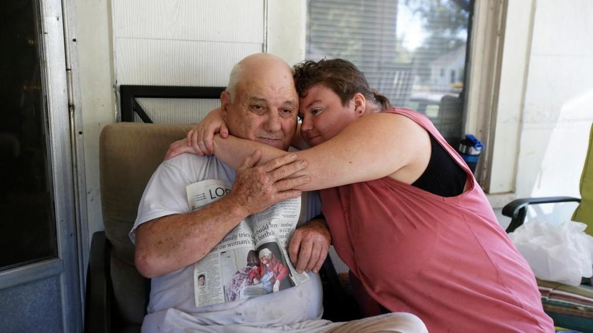 
The Wright family of adults with disabilities and other problems lost their mother last month at age 81 – and with her the basic money from Social Security that kept the bills paid. Now the family of four can’t find money to pay an electricity due this week and the rent is coming up in days and the future looks bleak. On Monday, Andy Wright gets a hug from his daughter, Michelle Wright, as he holds a 2013 edition of The Herald, showing a photo of his mother, Martha Wright, when their house burned.
