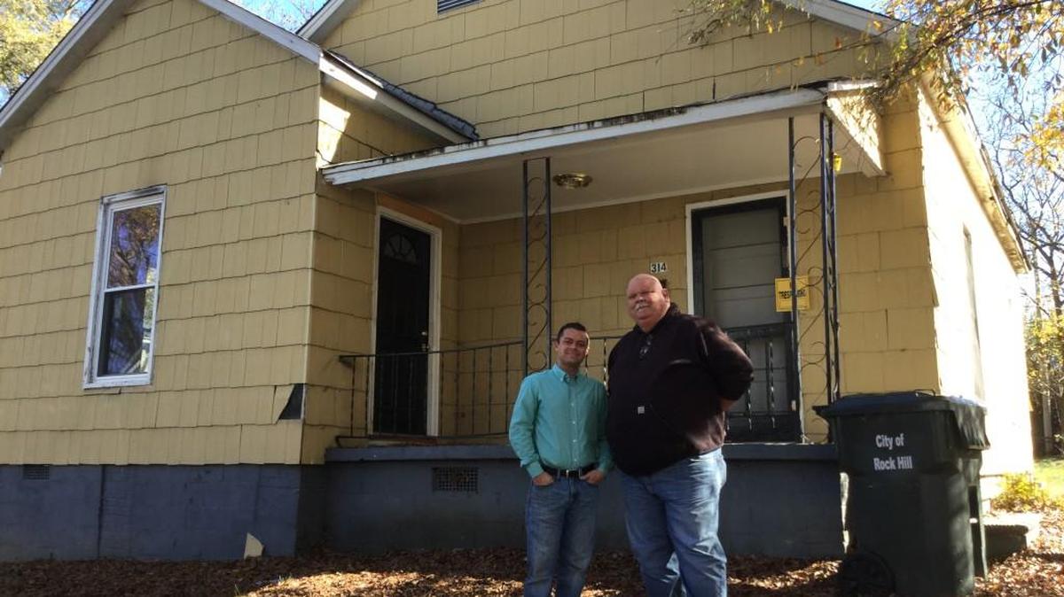 The Rev. Jonathan Pannell, left, and Paul Elkins stand in front of the house that will fulfill the dying wish of Elkins’ daughter, Emily.