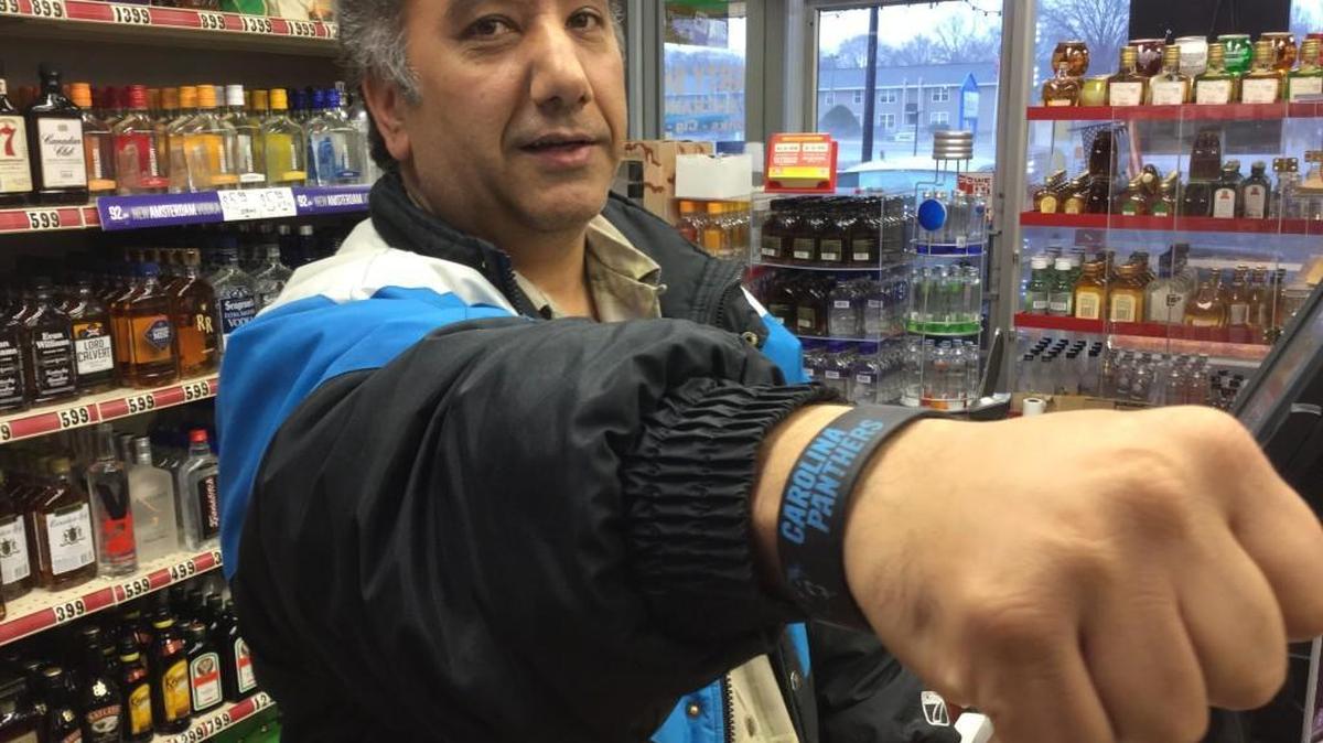 Mark Kaveh, an immigrant from Iran and Carolina Panthers superfan who lives in Rock Hill, shows his Panthers pride at his store.