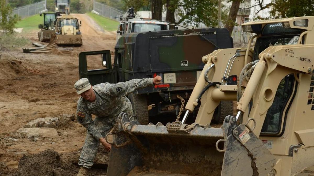 U.S. Army 1st Lt. Paul Bennett, an engineer from the South Carolina National Guard's 1782nd Engineer Company from Lancaster, uses hand signals to direct a heavy equipment operator with fill-dirt placement as their unit repairs a section of Whitehouse Road, near the Richland Wastewater Treatment Plant in Columbia. Veterans Day is a way to honor these other National Guard soldiers who help so many recover from the state’s flooding.