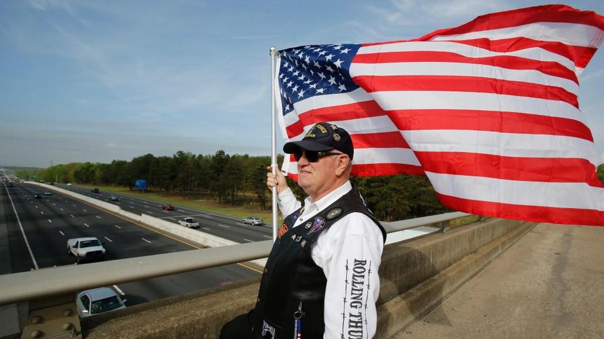 
Harvey Mayhill waves the American flag from the Sutton Road bridge over I-77 in Fort Mill.
