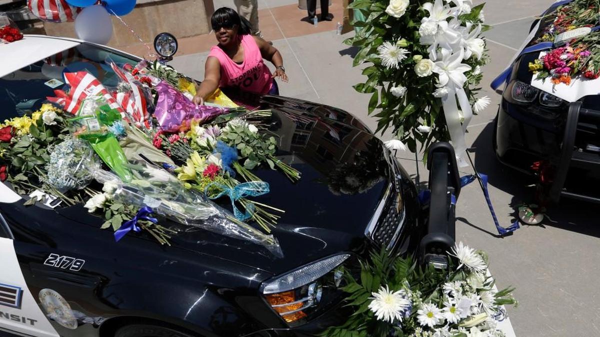Cynthia Ware places flowers on a make-shift memorial at the police headquarters Friday in Dallas. Five police officers are dead and several injured following a shooting in downtown Dallas on Thursday night.