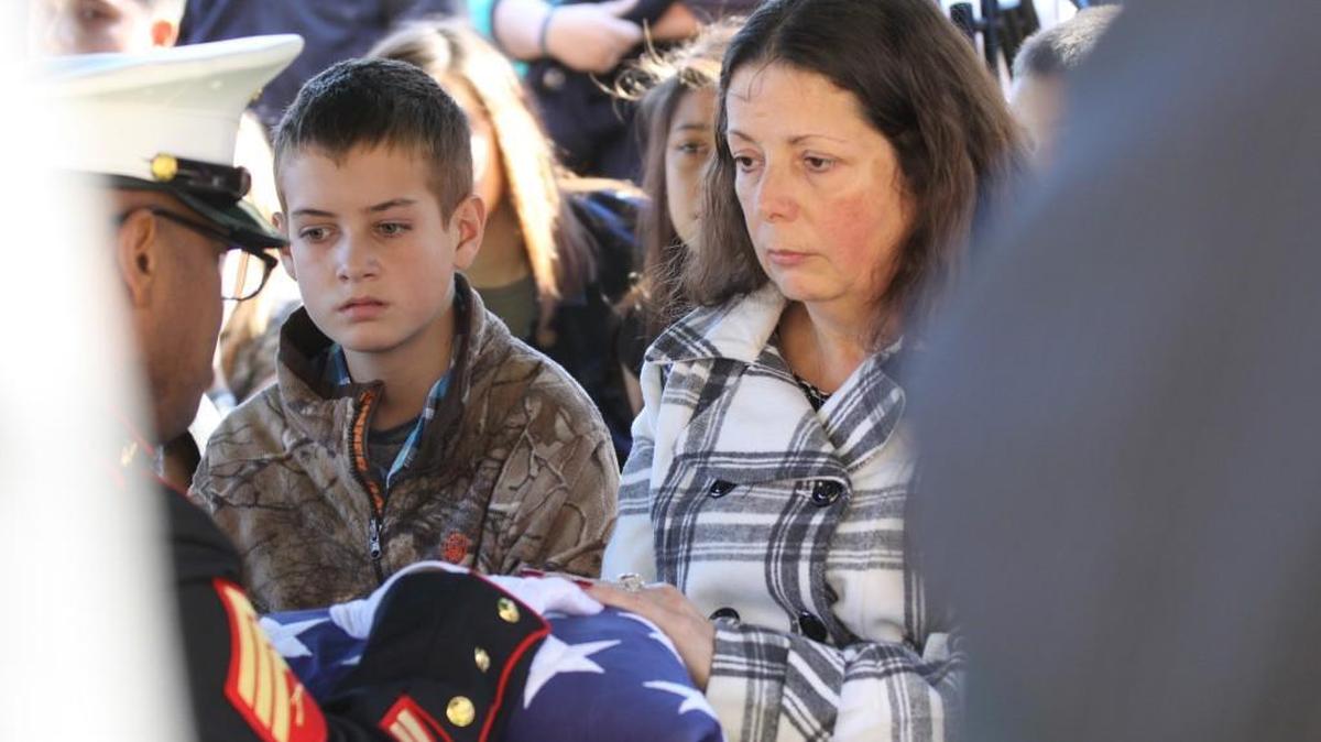 A member of a Marine Corps honor guard presents the tri-cornered folder flag to Cindy George, the widow of Catawba Indian Nation Assistant Chief Wayne George, and grandson Dylan George.