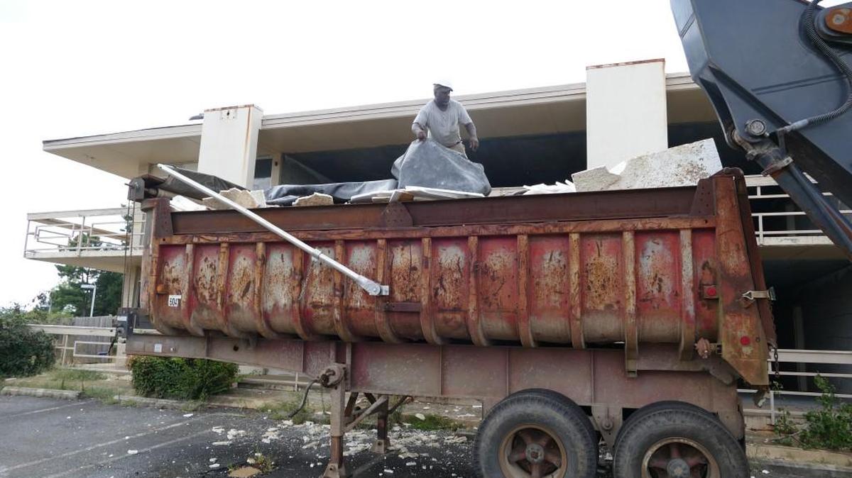 
Work crews with D.L. Hauling and Grading piled debris from the Executive Inn in a dump truck. Demolition of the condemned motel has resumed after health officials cleared it of asbestos.
