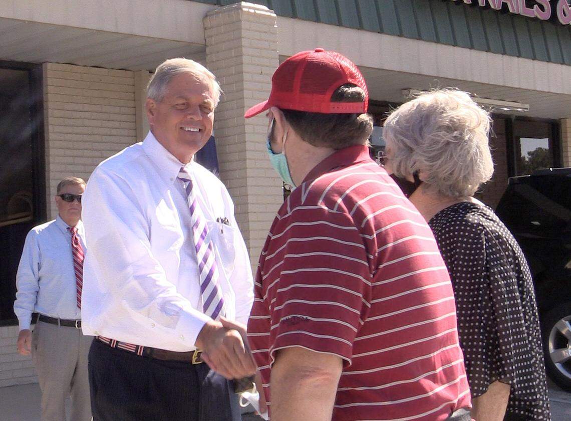 A maskless Congressman Ralph Norman, left, shakes hands with supporters Monday in Rock Hill.