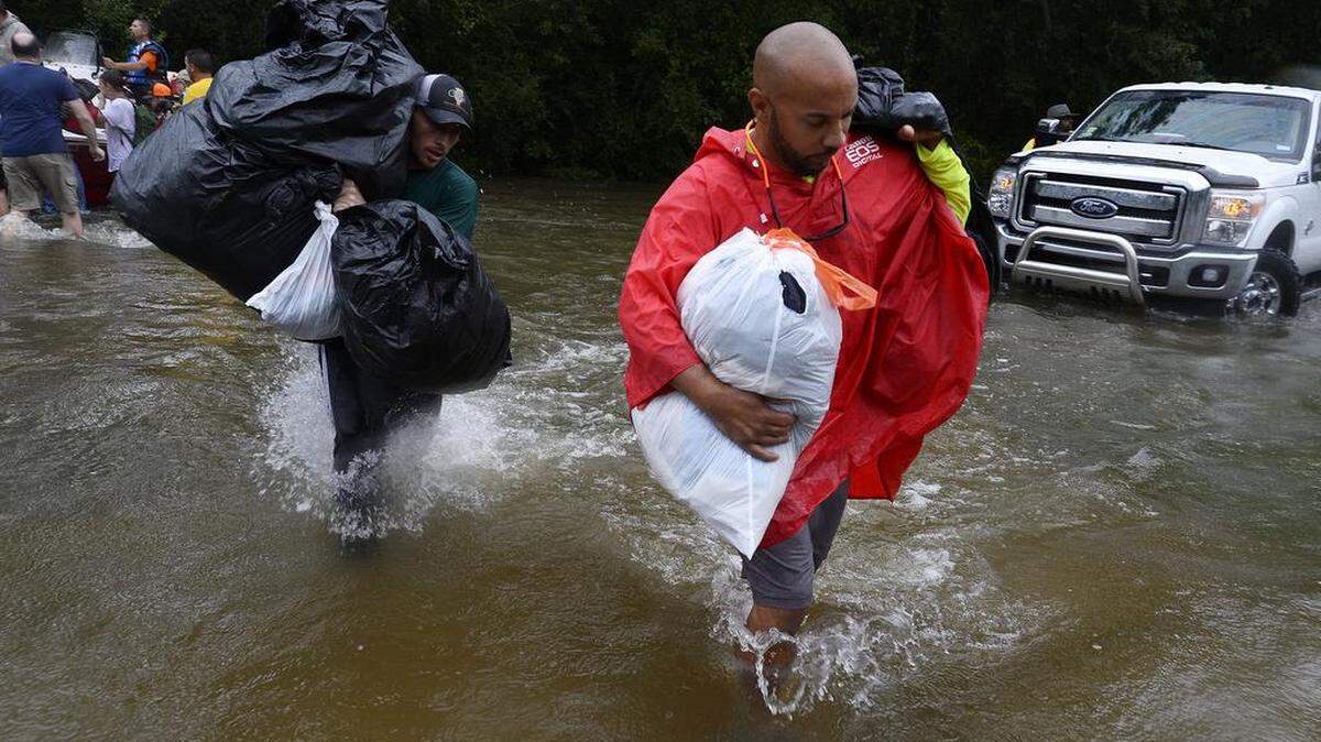 Volunteer Derek Burke, right, helps carry a family's belongings after boaters rescued them from flooding in the aftermath of Harvey in Beaumont, Texas on Aug. 30. Gov. Greg Abbott said Wednesday that "the worst is not over" for southeastern Texas as widespread flooding continues.