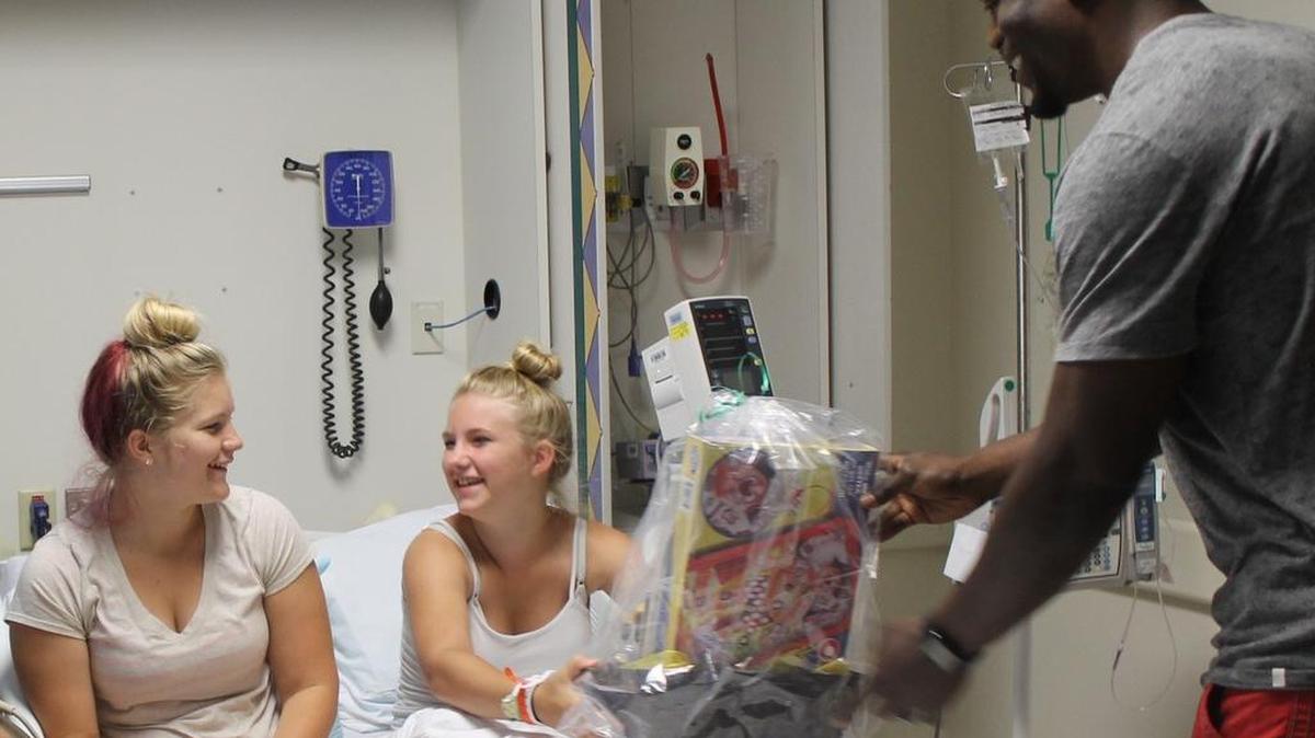 Ben Watson delivers a “basket of hope” Monday to 12-year-old Kylie Donaldson, center, and a friend who was visiting her at Piedmont Medical Center.