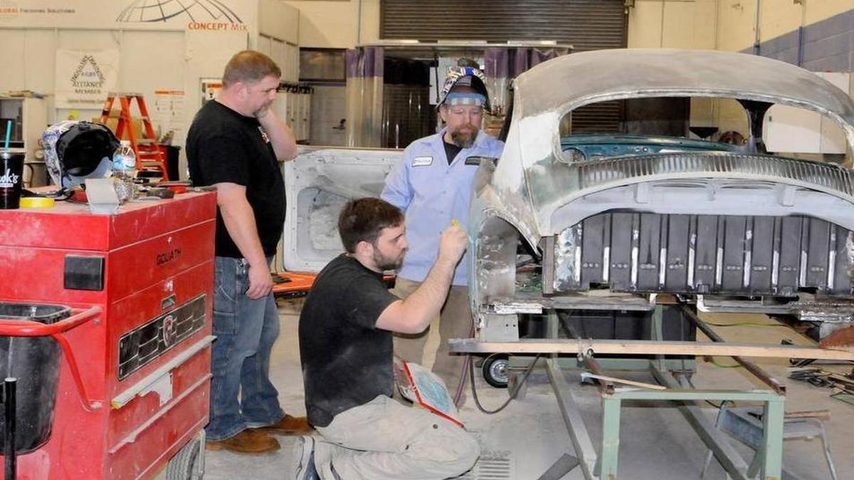 Applied Technology Center automotive instructors Gil Valk, left, and Mark Dellinger and Brian Slade, an advisory board member, discuss their work on a “rat rod” car that was built earlier this year by instructors and students.