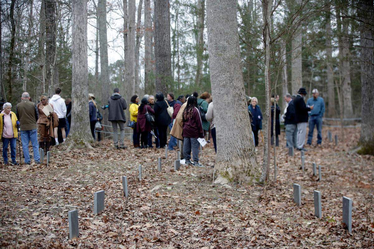 A group of people gathers at a cemetery on the property of Andrew Lazenby, where 144 enslaved people are buried.